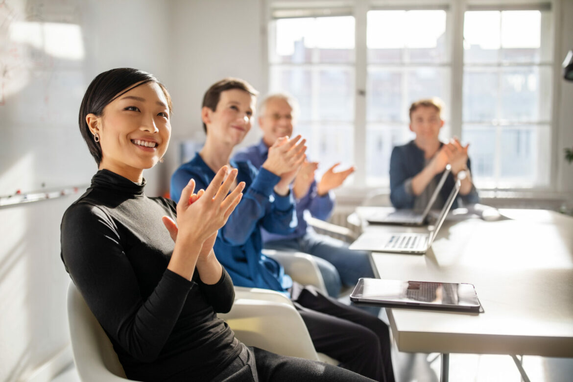 Business people applauding in board room. Business professionals clapping hands in a meeting.